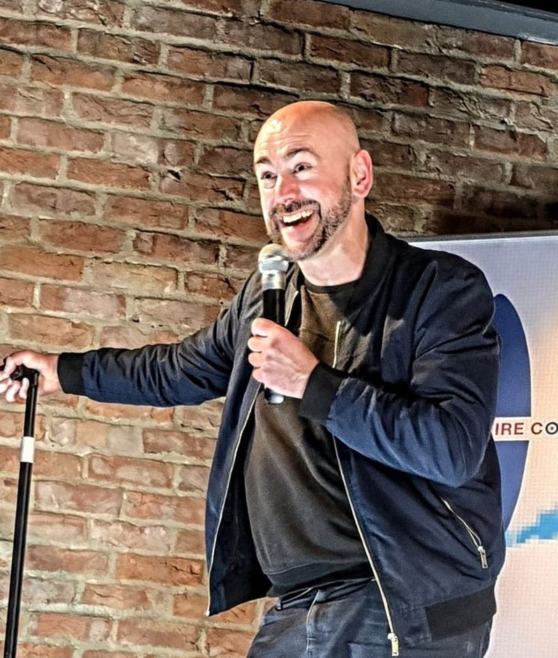 A comedian mid-set with the microphone at a Spitfire Comedy night